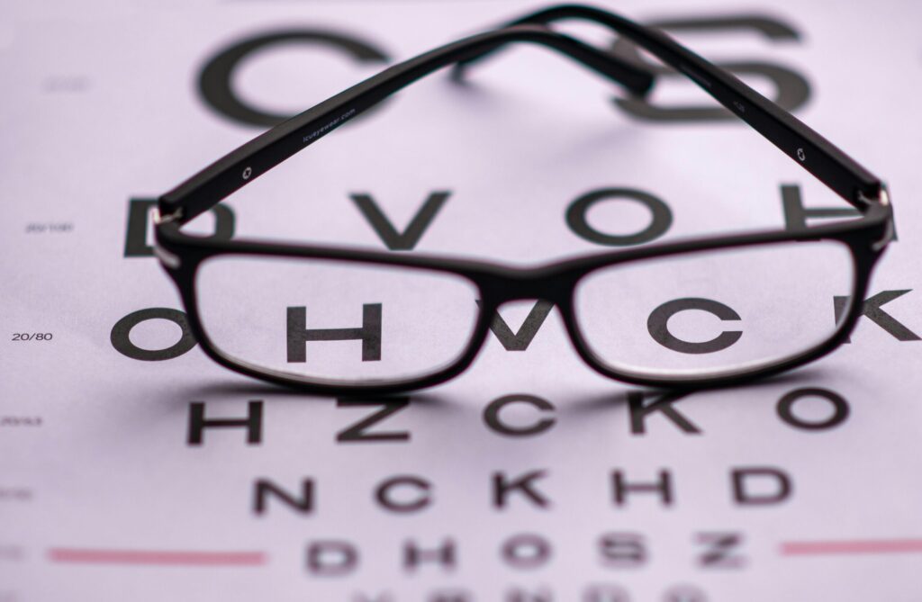 From above of classic eyeglasses placed on eye chart with letters in ophthalmologist room